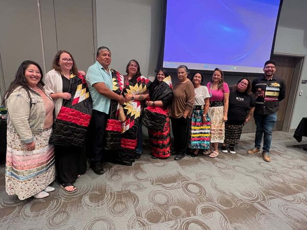 A group photo of people holding cloths of red, white, black and yellow.