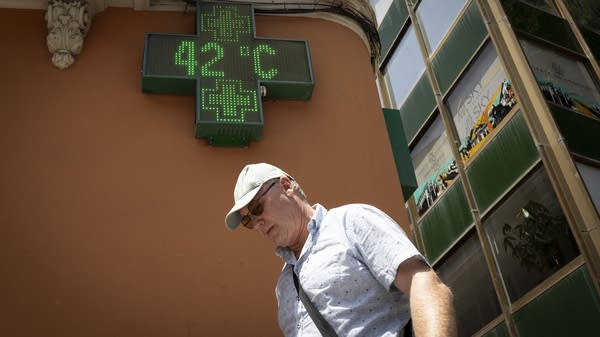 A man walks by a screen that shows 42 degrees Celsius.