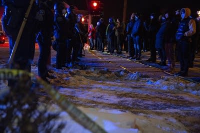 A%20crowd%20of%20people%20stand%20in%20front%20of%20a%20line%20of%20police%20officers.%20