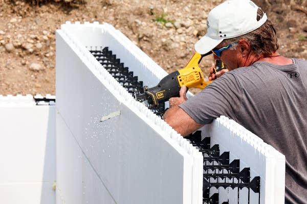 A person saws through concrete 