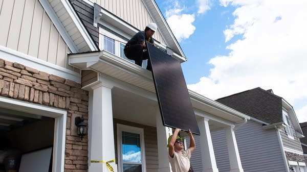 Panel installer Jack Cornwell passes a solar panel up to Cody Morgan on this roof in Concord, North Carolina. 