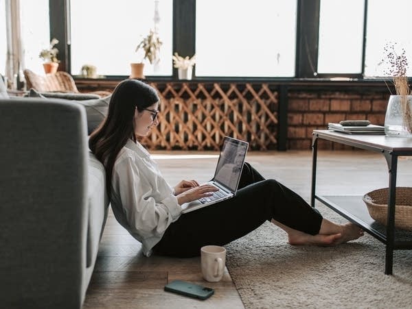 A woman works in a spacious home with a laptop.