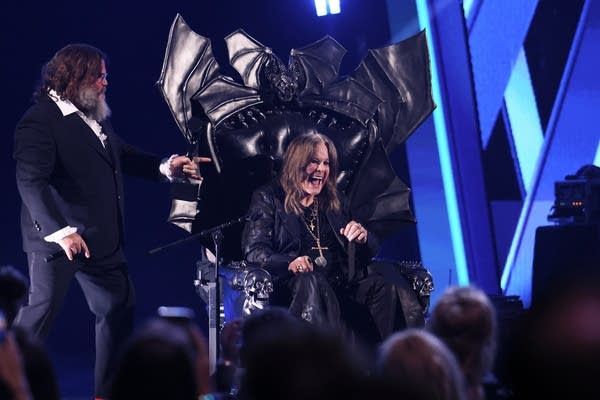 Two hirsute men interact onstage during an awards ceremony