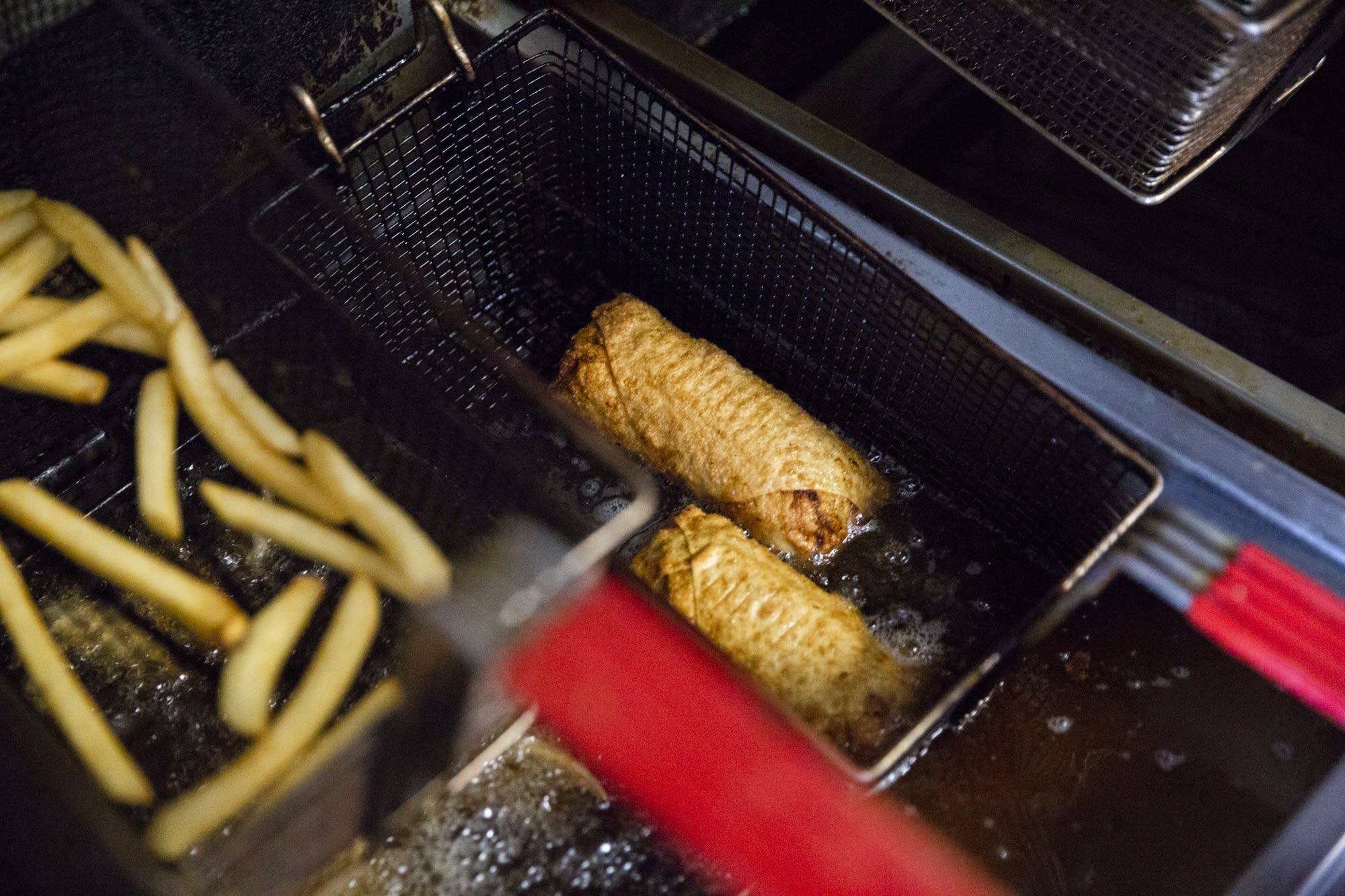Two soulrolls come out of a deep fryer.