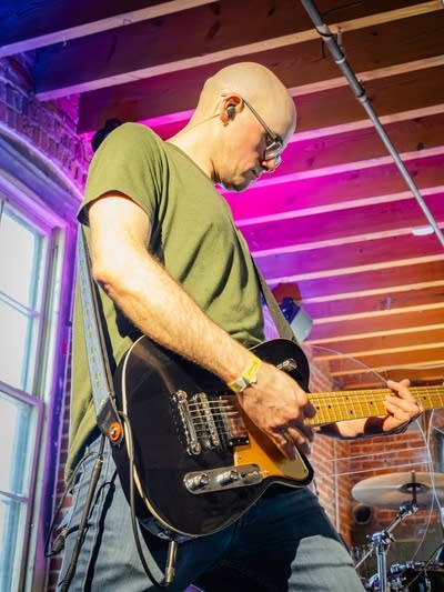 A musician plays guitar in a small music venue