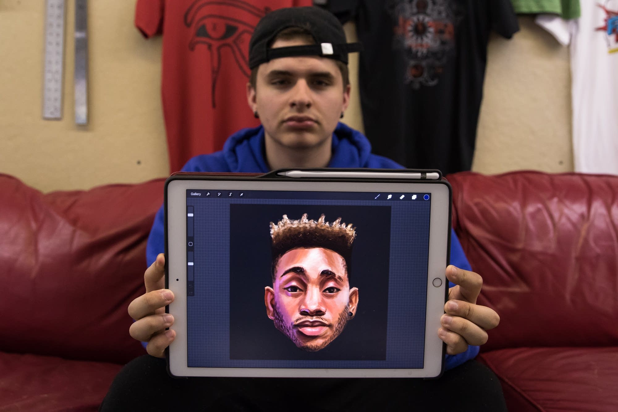 Senior designer Patricio Delara, 19, poses with a portrait.