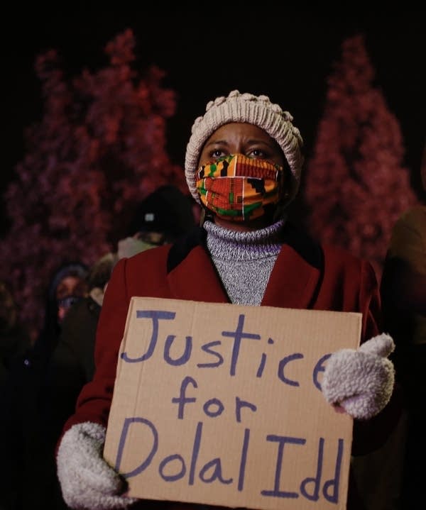 A person holding a sign that reads justice for Dolal Idd. 