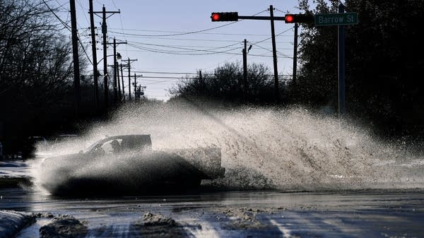 A pickup truck sends a spray of water from melted snow high into the air