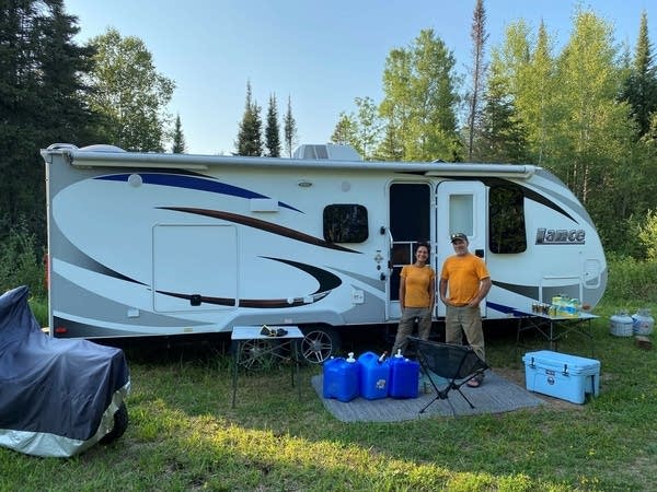 Two people outside their camper. 