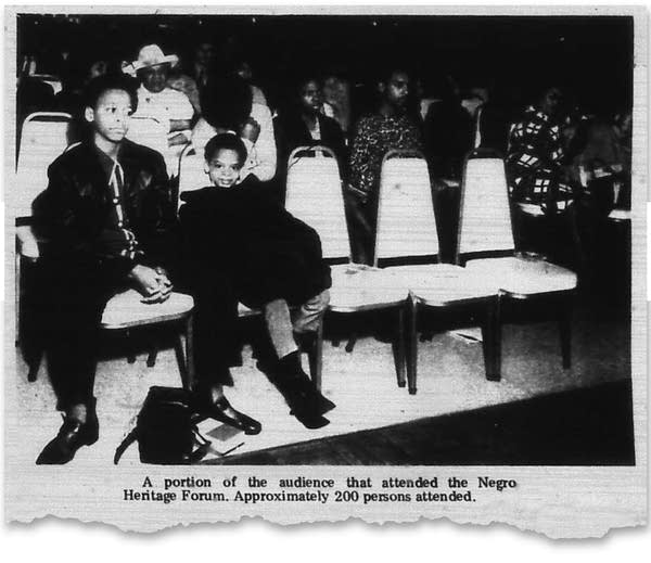 Two boys sit in chairs in a black and white photo from a newspaper.