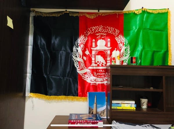The pre-Taliban Afghan flag (black, red and green vertical stripes) hangs on a wall.