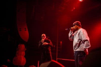 Two rappers perform onstage during a show in a music venue