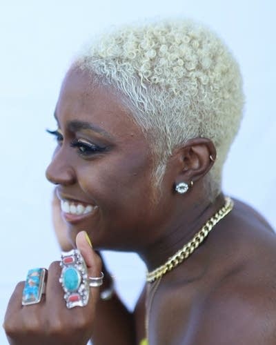 A women wearing rings on her fingers smiling and looking into the distance