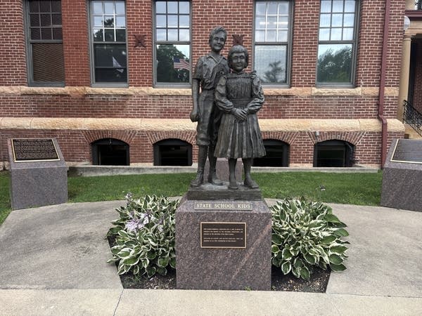 A statue of a young boy and young girl in front of a building.