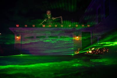 A giant skeleton climbs over a garage in a halloween display