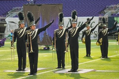 A marching band performs on the field of a football stadium.