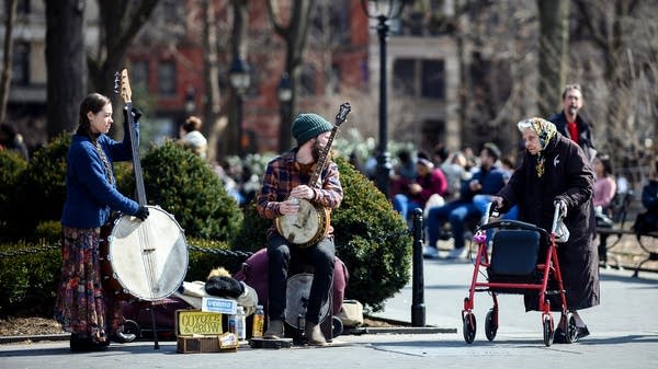An old woman talks to busker in a Park in downtown Manhattan on March 14, 2019 in New York City. Notice the musician's Venmo sign.