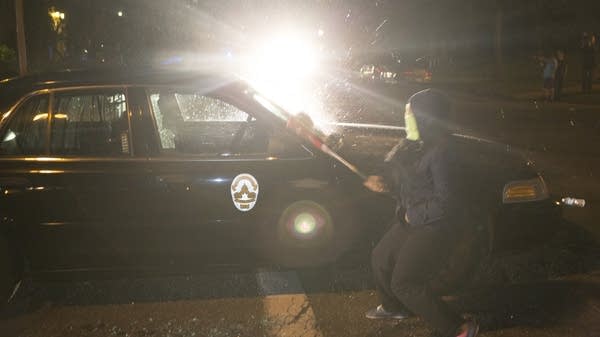 A protester smashed out a police squad car window.