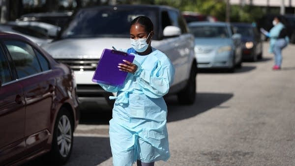 A health care worker helps organize drive-through COVID-19 testing in Florida. The industry has dealt with new pressures in the past year. 