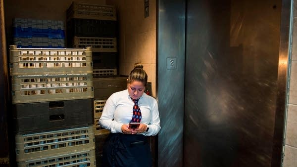 A waitress takes a break and looks at her phone in the Salvadorian and Latin American restaurant Lauriol Plaza in Washington, DC on January 11, 2018. 