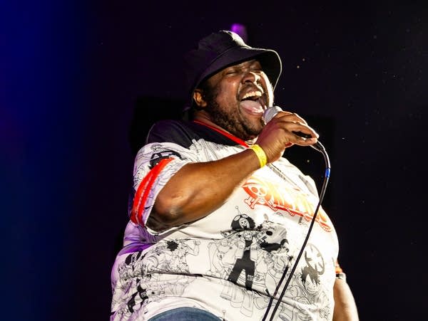 A hip-hop artist performs onstage in a small music venue