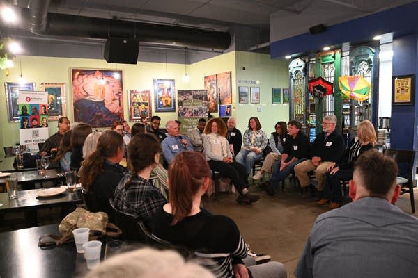 People gather in a space in the restaurant as one woman stands holding a microphone.