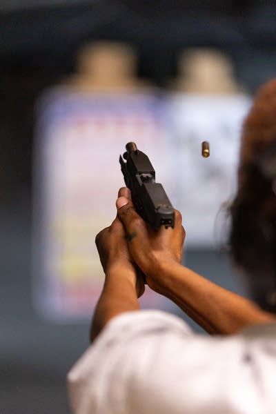 A person shoots a gun and a casing flies back