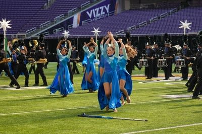 A marching band performs on the field of a football stadium.