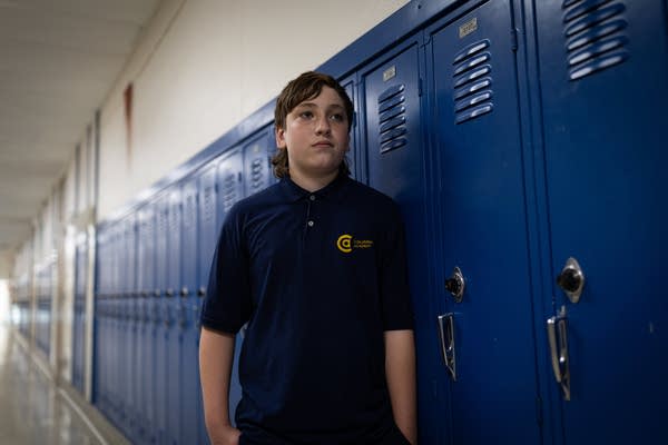 A student poses for a portrait next to a row of lockers