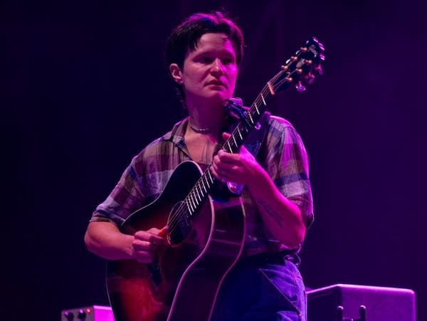 Adrianne Lenker plays acoustic guitar on stage