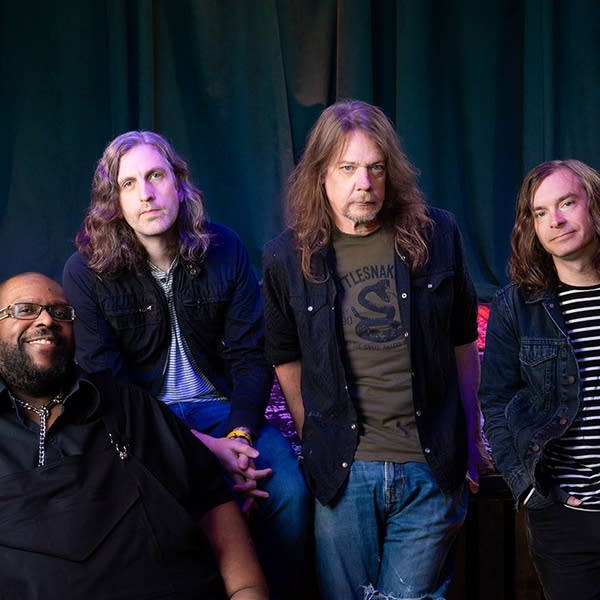 Four musicians sit together for a group photo