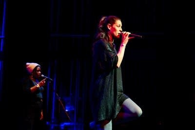 a woman singing on stage with a backup singer
