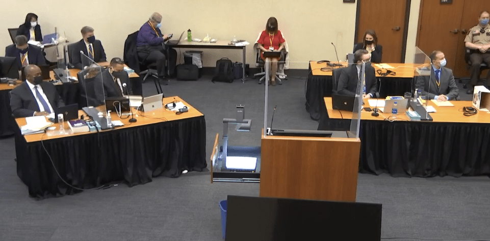 People sit behind desks in a courtroom.