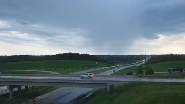 Storm clouds are visible above a freeway