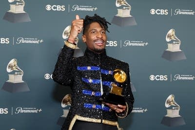 A man smiles while holding an award statuette he has just won