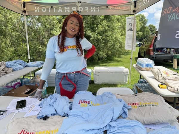 A woman poses for a photo while working a booth.