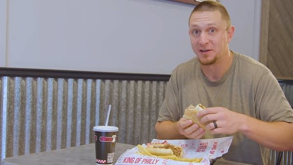 Giants outfielder Alex Dickerson holding a cheesesteak in a sandwich shop