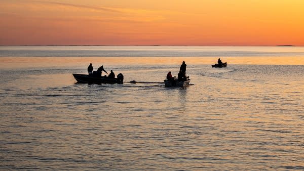 Fishing boats on a lake at sunset.