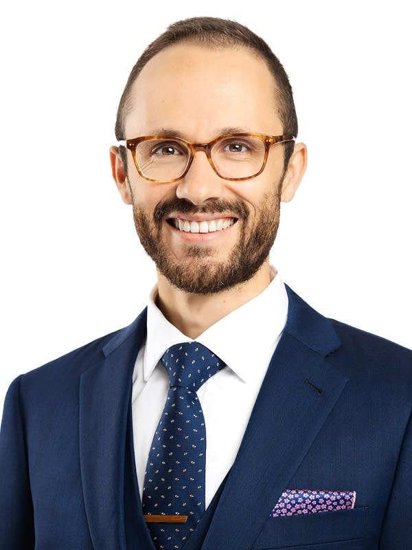 A man in a suit poses for a portrait