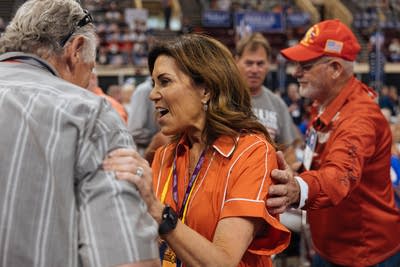 A woman shakes hands with people at the convention.