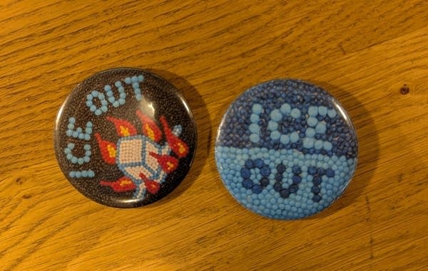 Two buttons reading "ICE OUT" sitting on a wood table.