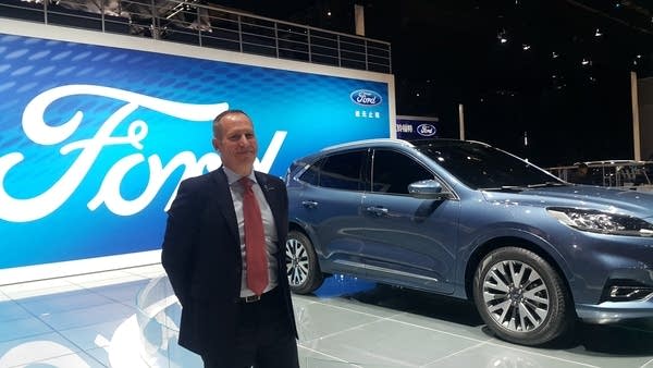 A Ford executive poses next to their new models at the Shanghai auto show.