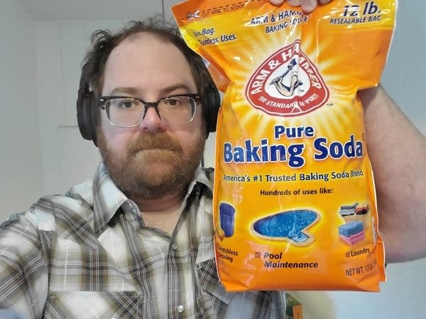 Andrew (white 43 year old man w glasses) holding 12 lb bag of baking soda.