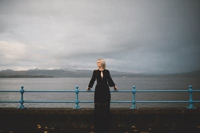 A woman leans against a railing along a seawall