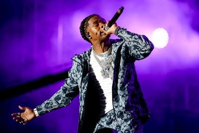 A man wearing bespoke jewelry and a tracksuit sings onstage