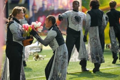 A marching band performs on the field of a football stadium.