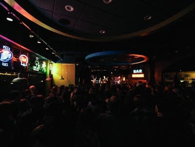 A band performs inside a packed music venue.