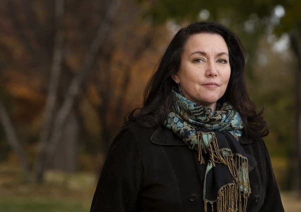 A woman wearing a blue patterned scarf and black coat.