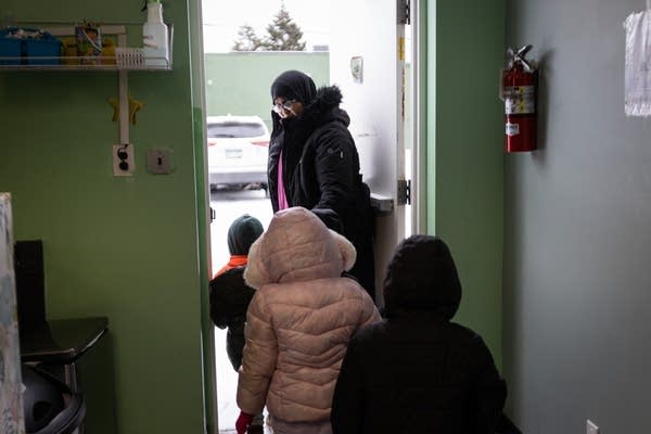 A woman leads children through a door