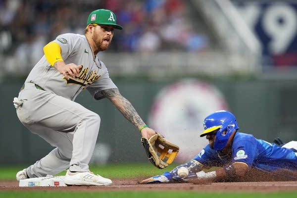 A player attepting to catch baseball while another player slides into bag